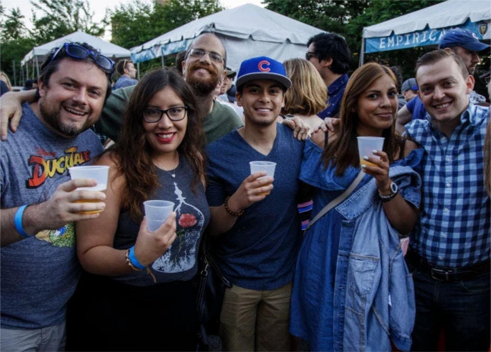 An outdoor festival, people smiling and holding beer