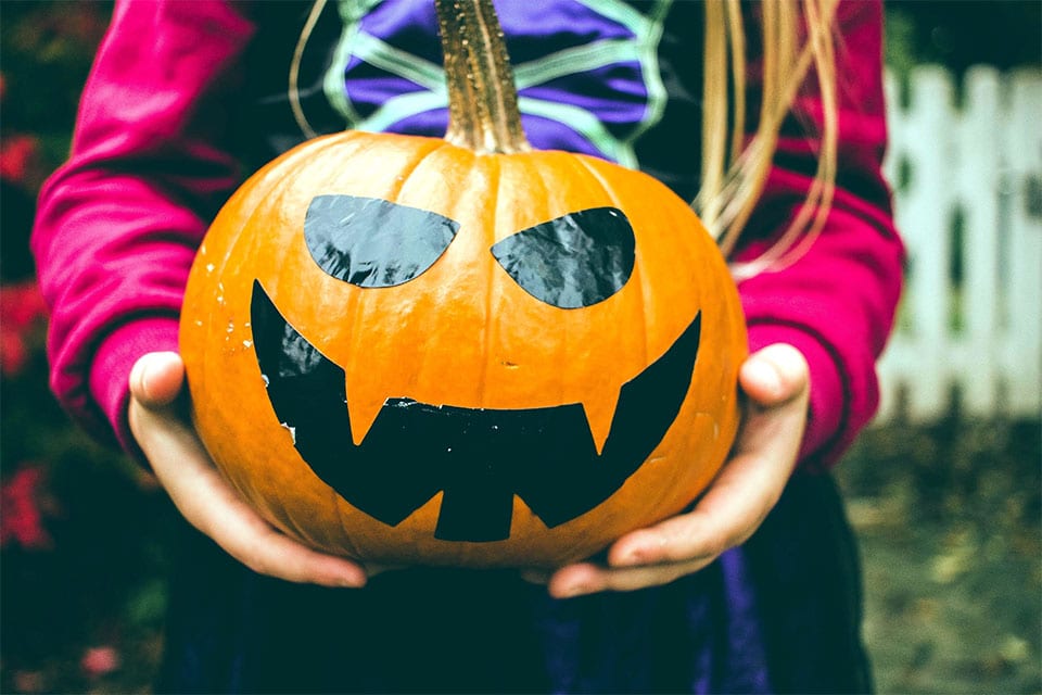 A photo of a girl holding a jack-o-lantern